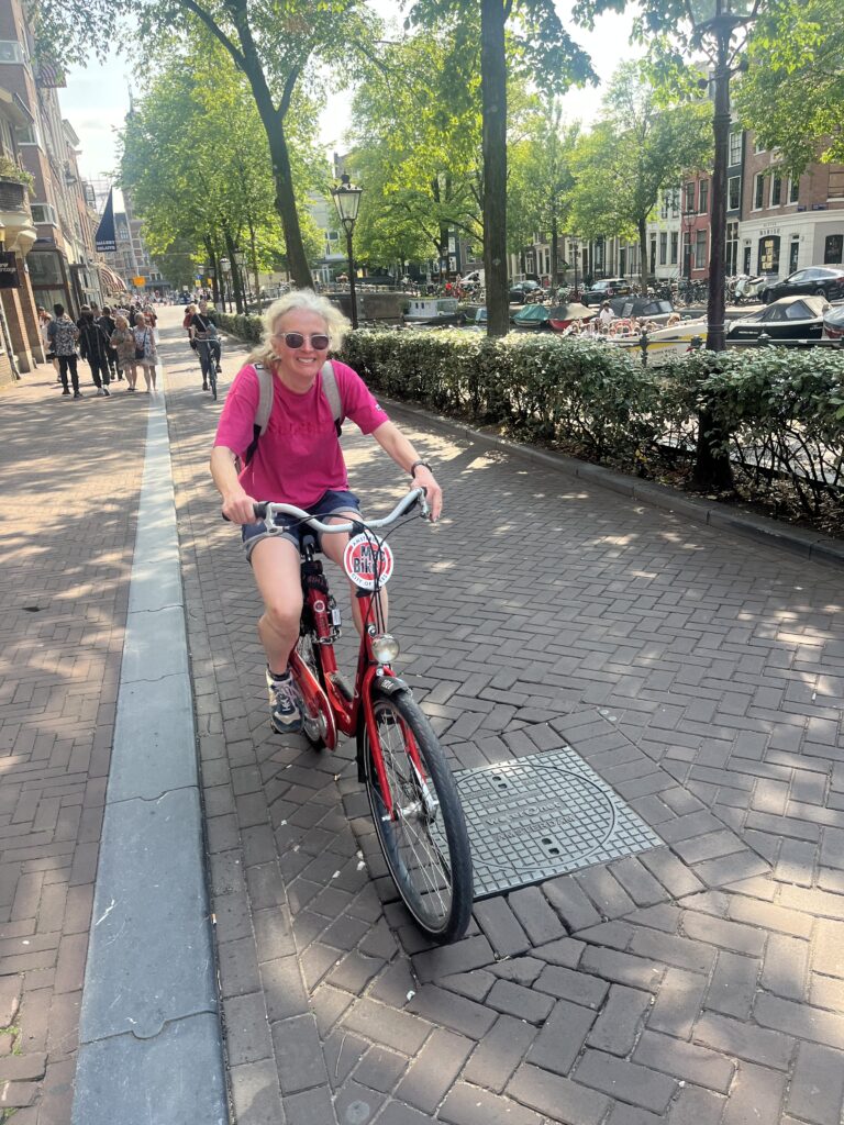 Bike hire, Amsterdam, Woman in pink Tshirt and sunglasses on a red bike