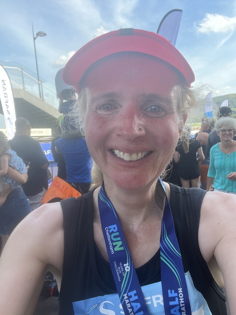 Cheltenham half marathon, Cheltenham half marathon medal, Running, Runner, Head and shoulders photo of a female runner in a black vest and pink cap wearing a medal