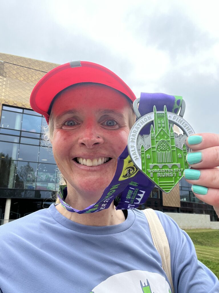 Worcester City half marathon medal, Worcester City half marathon, A female runner in a pink cap and light blue top holds a medal