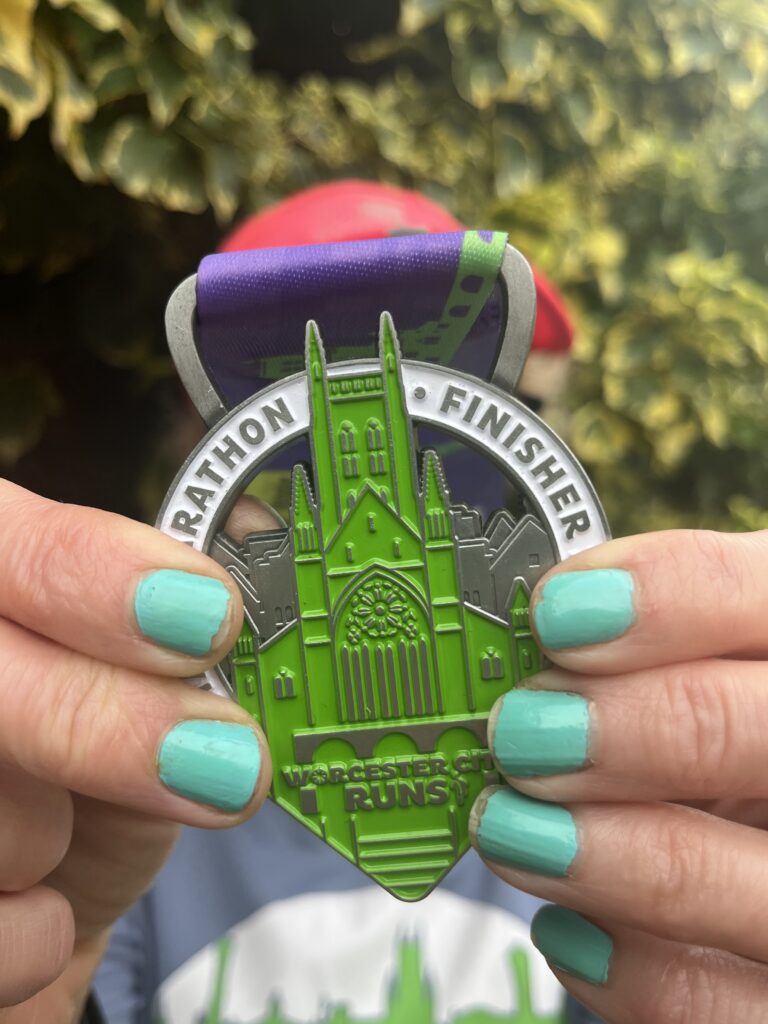 Worcester City half marathon medal, Close up photo of a medal held by a woman with blue nails