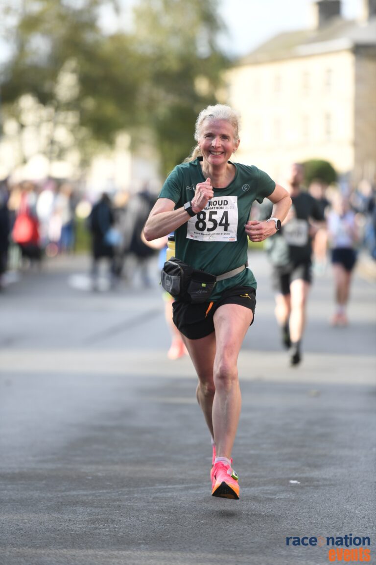 Runner, Running, Stroud half marathon, Female runner in green Tshirt and black shorts smiles as she runs
