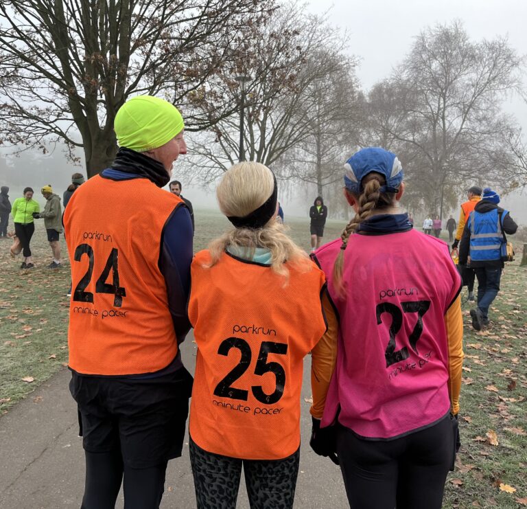 Parkrun pacing, Parkrun volunteering, Runners, Running, One male and two femal runners have their backs to the camera and are wearing bibs with numbers on - 24 25 and 27
