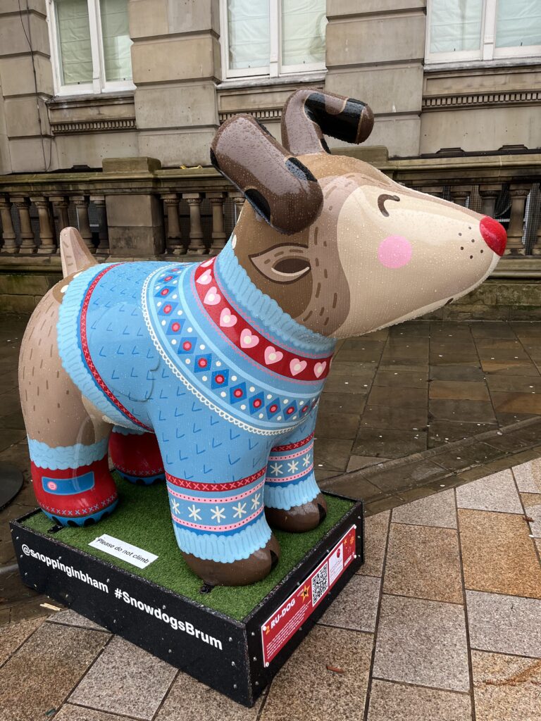 Snowdog, Birmingham, SnowdogsBrum, Silent Sunday, My Sunday Photo, Sculpture trail, A sculpture of a cartoon dog pained as Rudolph the red nosed reindeer in a blue Christmas jumper stands on a rainy street