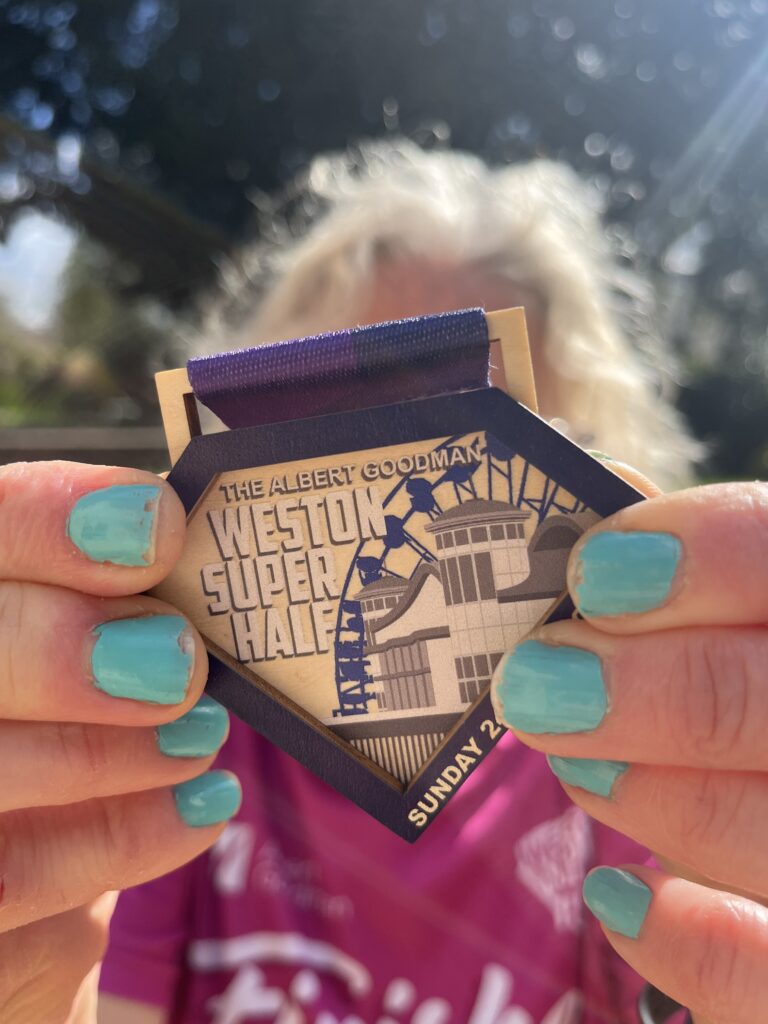Weston Super Half medal, Weston Super Half, Half marathon, Medal, Running, Runner, Silent Sunday, My Sunday Photo, Close-up of a wooden medal which says Weston Super Half held by a woman with blue nails