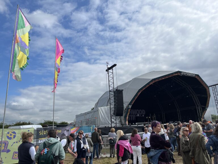 Wychwood Festival, Festival, Cheltenham, Gloucestershire, Silent Sunday, My Sunday Photo, A stage in front of a blue sky and a crowd of people with large coloured flags