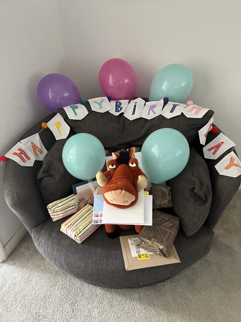 Silent Sunday, My Sunday Photo, Birthday presents, Pumbaa, A Pumbaa toy with presents cards balloons and a happy birthday banner sit on a round dark grey armchair