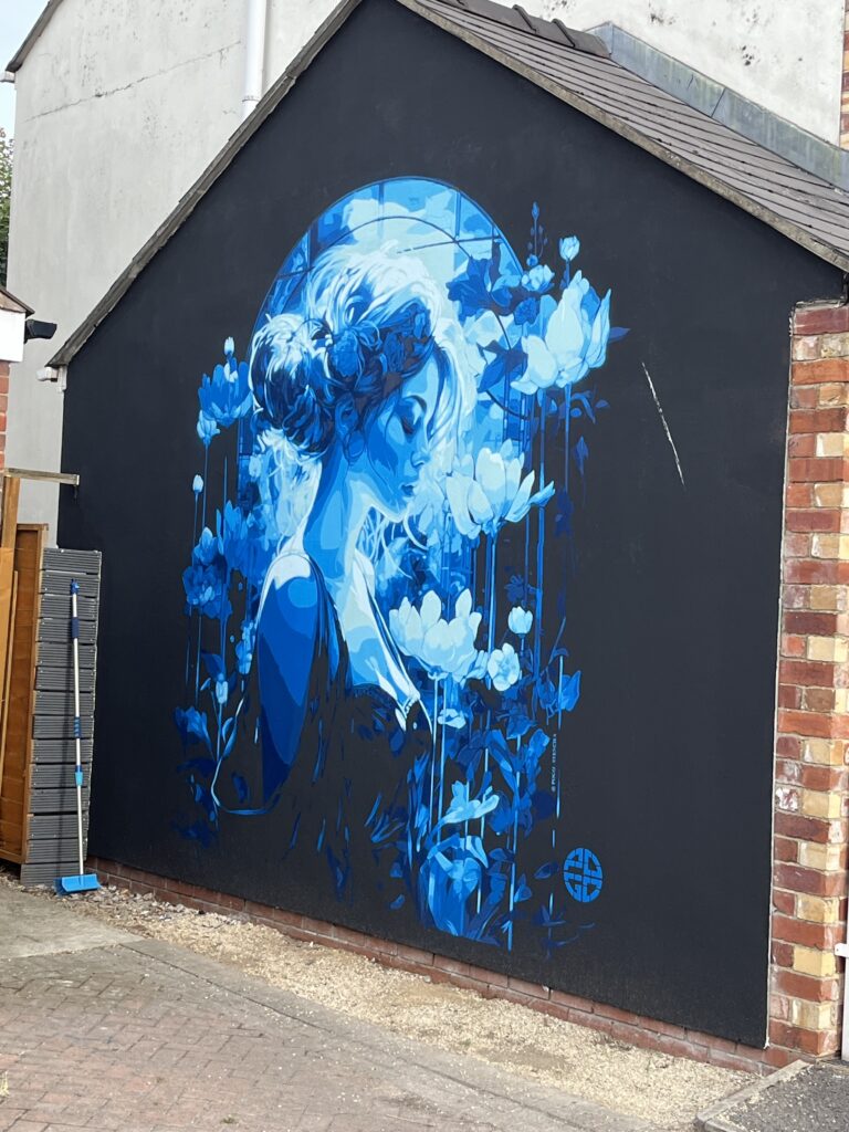 Cheltenham Paint Festival, Street art, Silent Sunday, My Sunday Photo, A beautiful portrait of a woman surrounded by flowers all painted in blue on a black background on the side of a house
