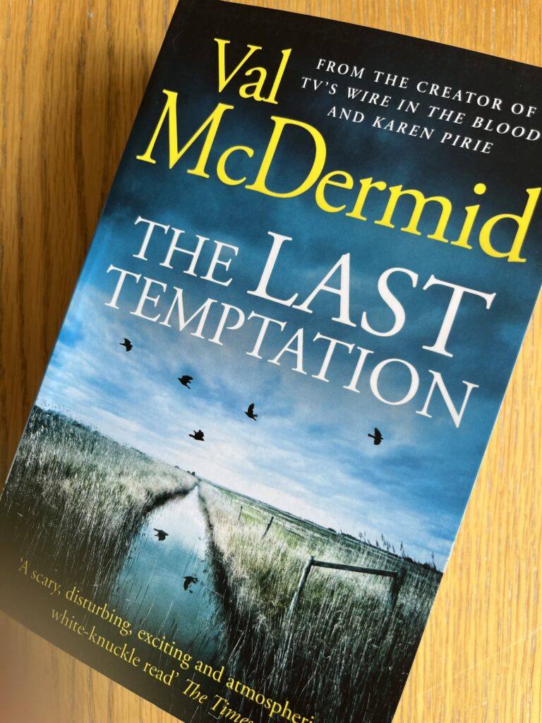 The Last Temptation by Val McDermid, The Last Temptation, Val McDermid, The Last Temptation by Val McDermid, A book with a dark blue cover called The Last Temptation by Val McDermid sits on a wooden table
