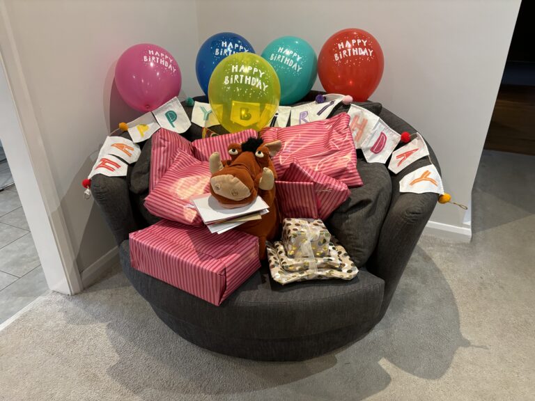 Birthday, 51st birthday, Balloons, Birthday presents, Pumbaa, Silent Sunday, My Sunday Photo, A pile of birthday presents sits on a round grey armchair with a toy Pumbaa from The Lion King in the middle and colourful birthday balloons