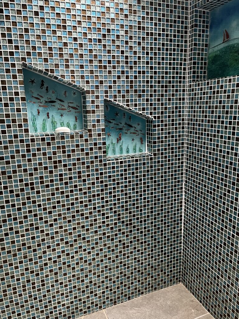 Padstow, Holiday, Holiday home, Shower room, Off-peak holiday, A room entirely tiled with tiny blue and brown shiny tiles and a couple of small inset shelves with glass sea scenes