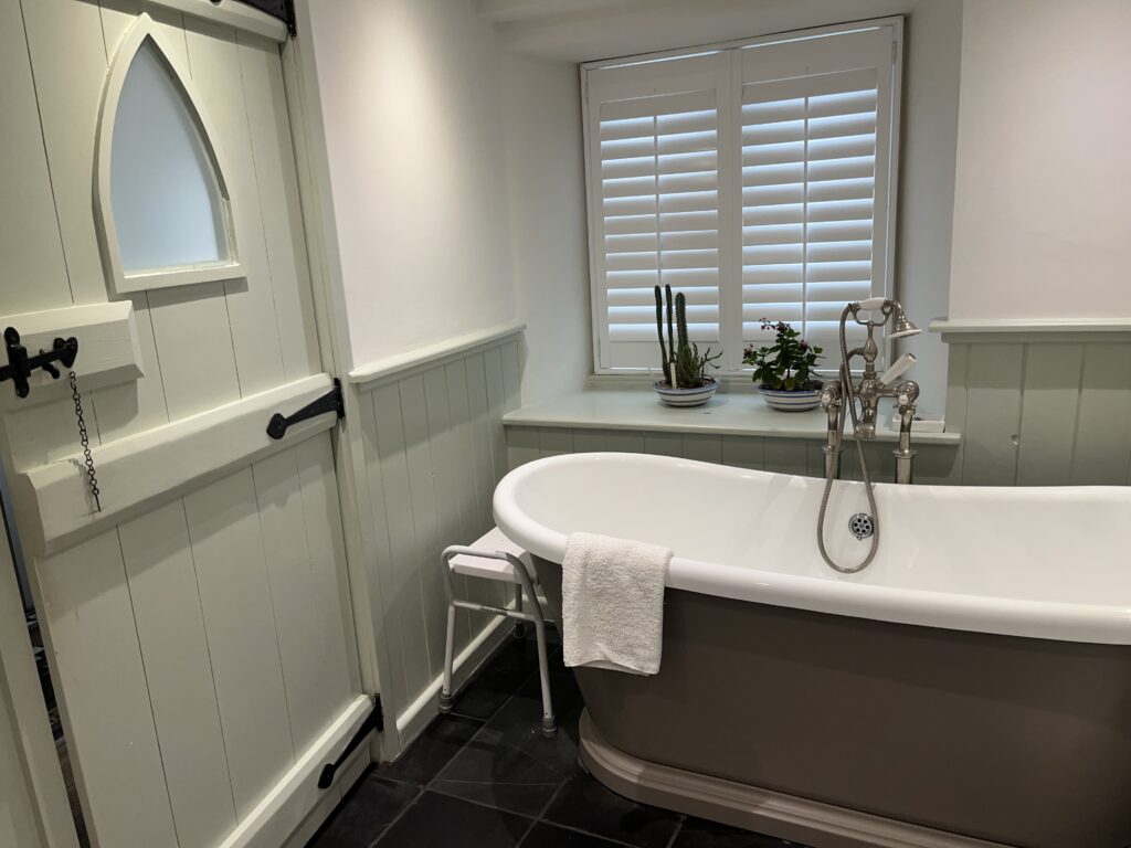 Padstow, Holiday, Bathroom, Holiday home, A roll top bath and an old fashioned wooden door with an arch window in it and a big window with white shutters