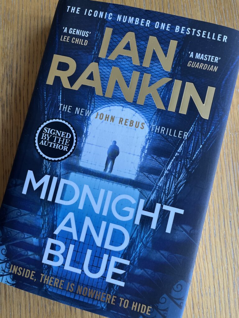 Midnight and Blue by Ian Rankin, Midnight and Blue, Ian Rankin, Rebus, A dark blue book called Midnight and Blue by Ian Rankin sits on a wooden table