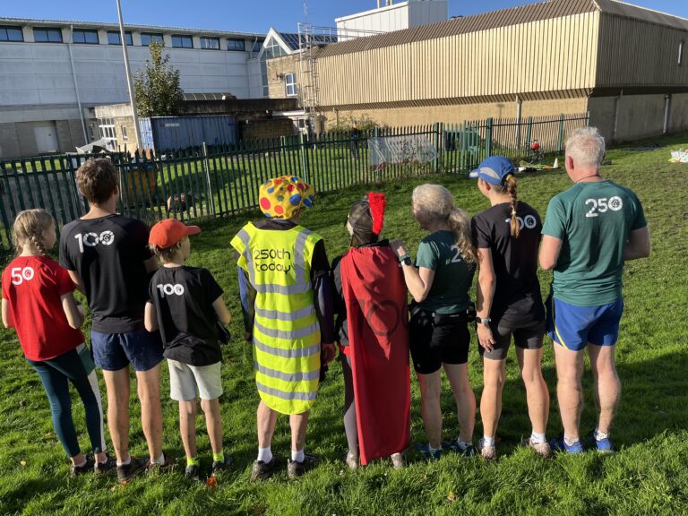 Parkrun, Family, Parkrun milestones, Silent Sunday, My Sunday Photo, A line of eight people seen from behind all dressed for running with Tshirts with numbers on the back and the two in the middle have special outfits