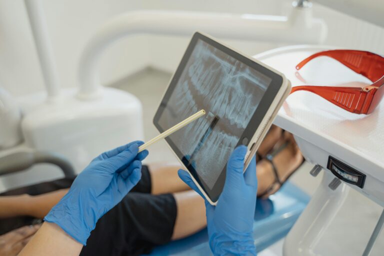 Root canal, Dentist, Dental, Close up of hands in blue surgical gloves holding an iPad with an xray of teeth on it