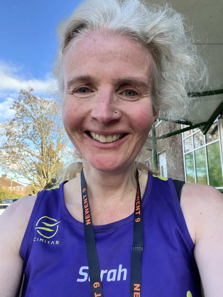 Newent 9, Running, Runner, Newent, Gloucestershire, Head and shoulders photo of a smiling female runner in a purple vest with a medal round her neck