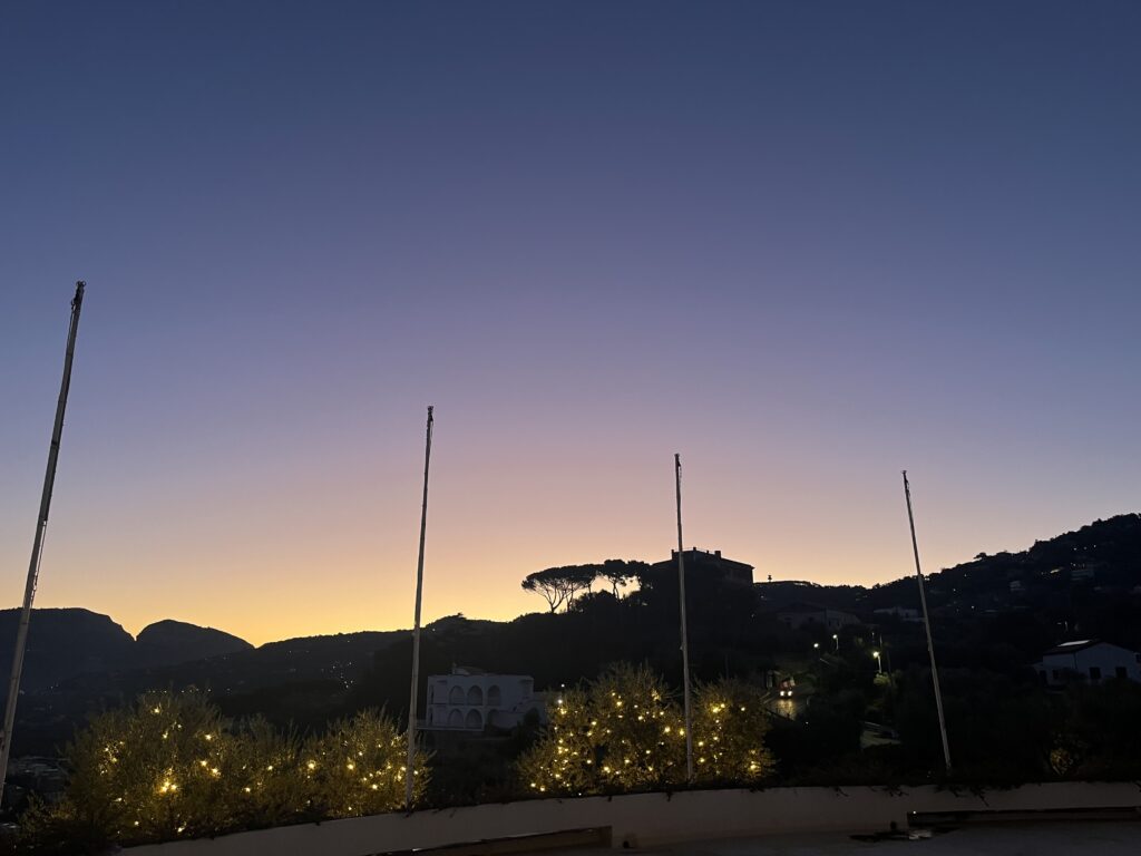Sorrento, Sunrise, Grand Hotel Aminta, Italy, Silhouetted hills trees and buildings against a pale blue pink and yellow sky