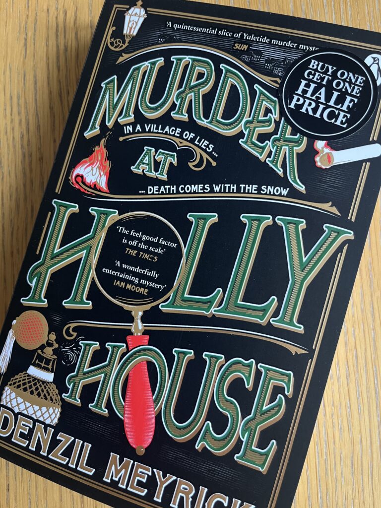 Murder at Holly House by Denzil Meyrick, Murder at Holly House, Denzil Meyrick, Book review, A book with a black cover called Murder at Holly House by Denzil Meyrick written in green and gold sits on a wooden table