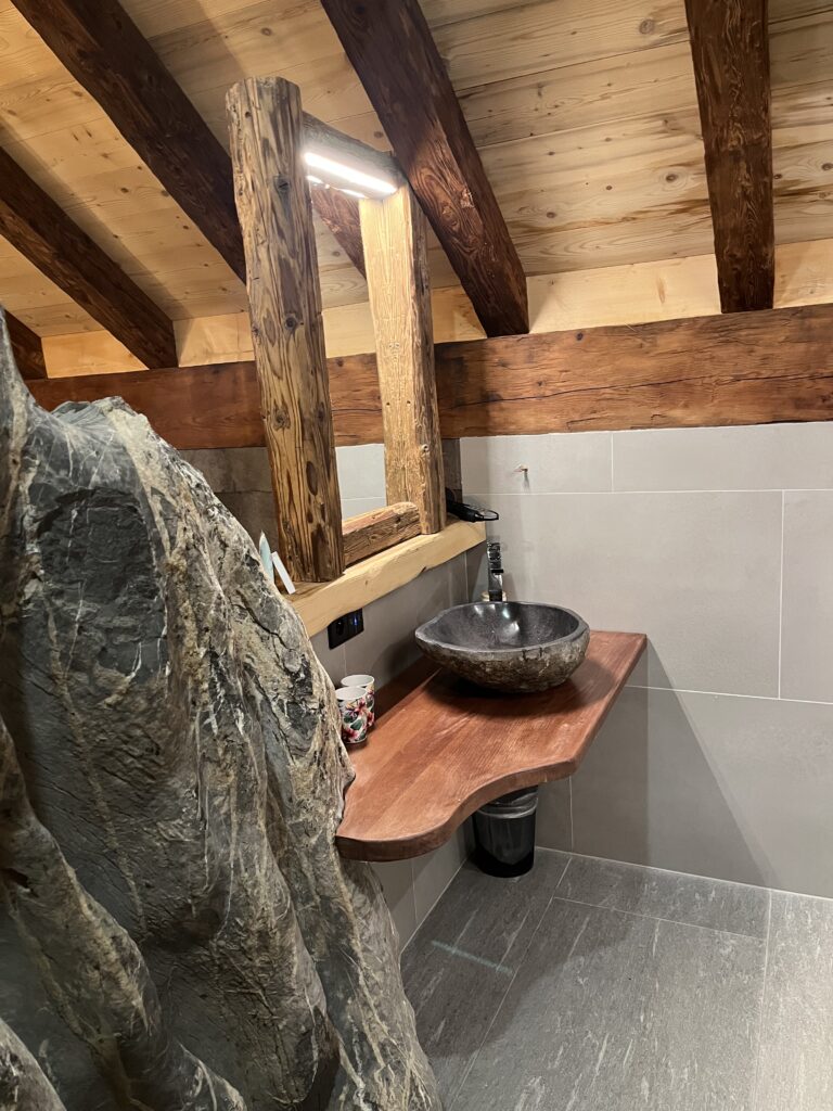 Hotel, Hotel bathroom, Skiing holiday, A stone sink on a wooden shelf in a room withe a wooden ceiling and tiled walls and floor