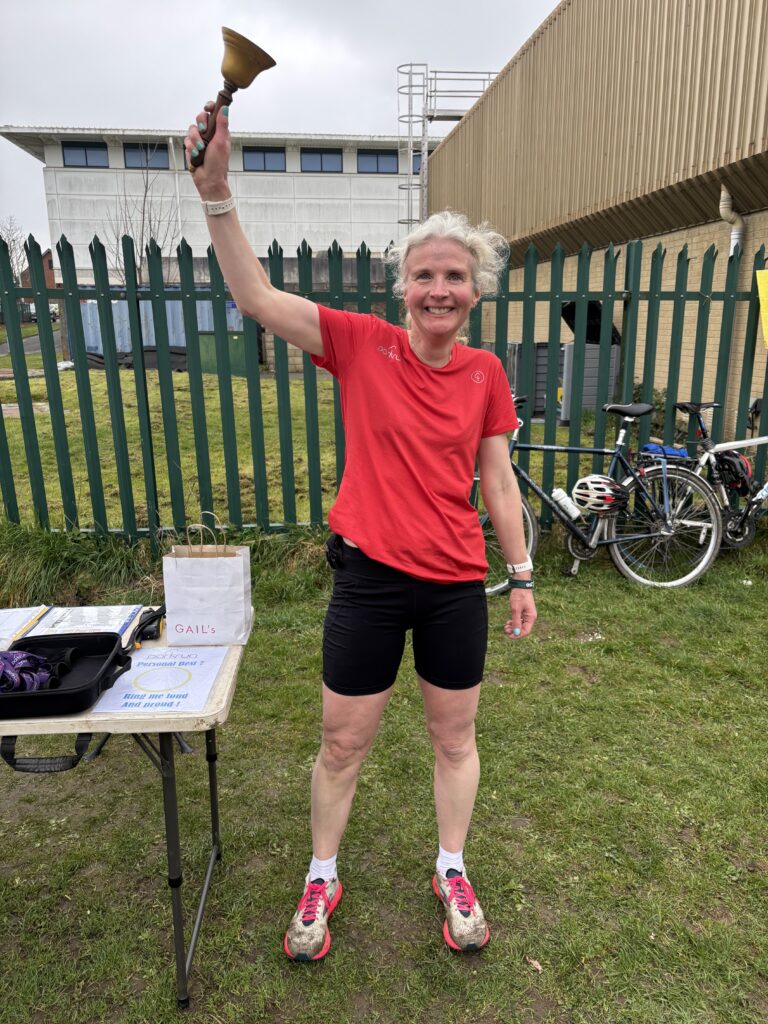 Parkrun, Parkrun PB, Running, Runner, Silent Sunday, My Sunday Photo, A smiling female runner in a red Tshirt and black shorts rings a bell above her head