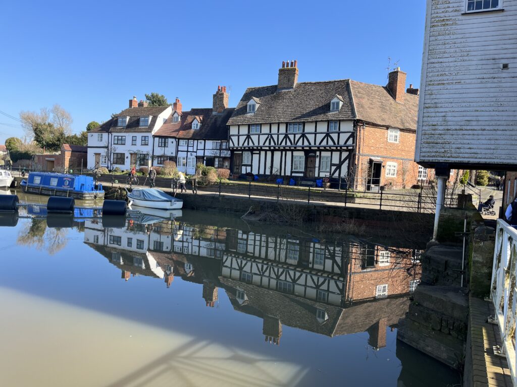 , A blue sky and some Tudor buildings reflected in a still river