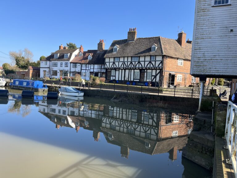 , A blue sky and some Tudor buildings reflected in a still river