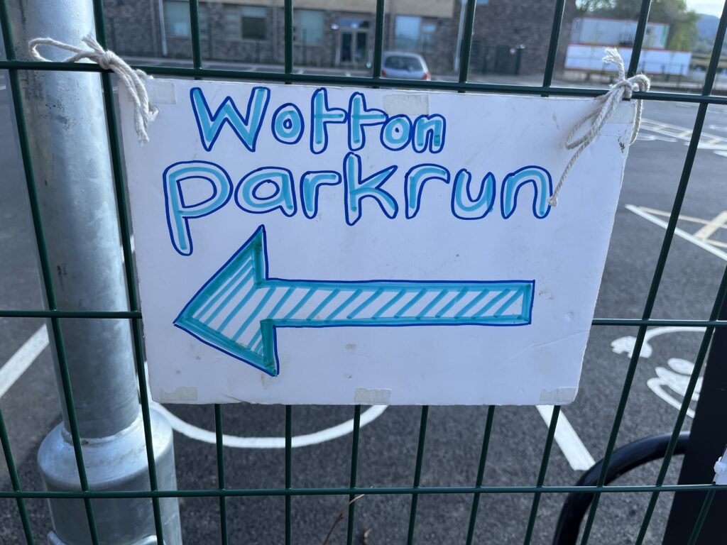 Wotton parkrun, Parkrun tourism, A hand drawn sign with Wotton parkrun in blue pen and an arrow is tied onto a metal fence with string