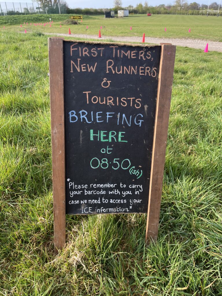 Wotton parkrun, Parkrun tourism, Running, A chalkboard sits on grass whish says First timers and tourist briefing here at 8:50