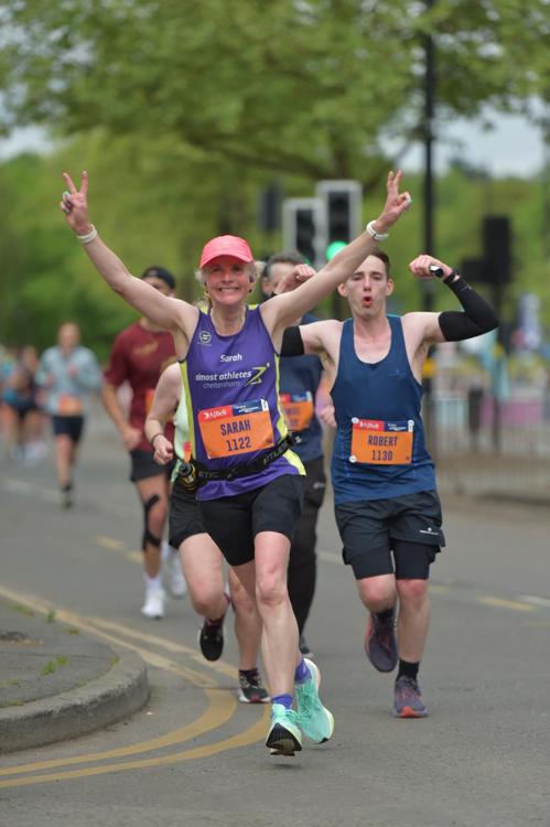 Great Birmingham Run half marathon, Running, Runners, Half marathon, A smiling female runner in a purple vest and pink hat with her arms in the air at the front of a pack of other runners