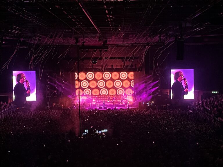 Pulp, Utilita Arena, Birmingham, Live music, Concert, Silent Sunday, My Sunday Photo, A concert hall filled with people with the stage in the distance and two screens with a purple background showing a singer wearing glasses