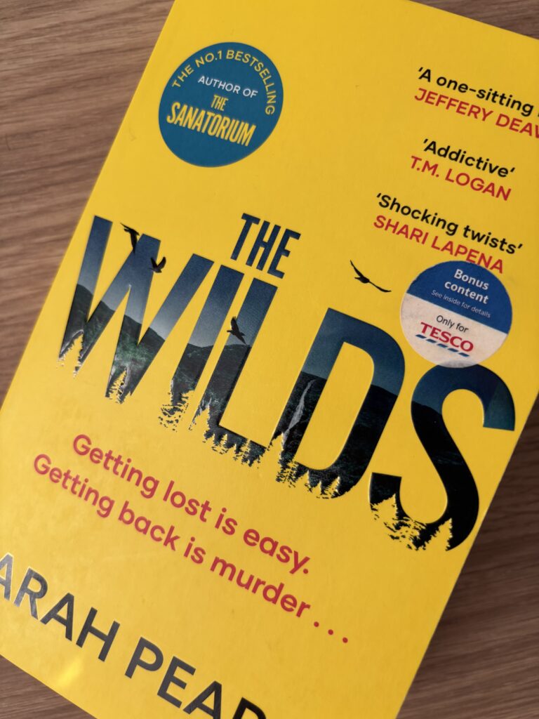 The Wilds by Sarah Pearse, The Wilds, Sarah Pearse, Book review, A yellow book called The Wilds by Sarah Pearse sits on a wooden table
