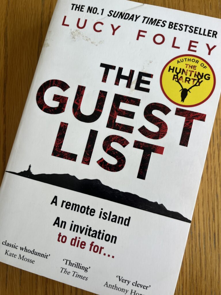 The Guest List by Lucy Foley, The Guest List, Lucy Foley, Book review, A white book called The Guest List by Lucy Foley sits on a wooden table
