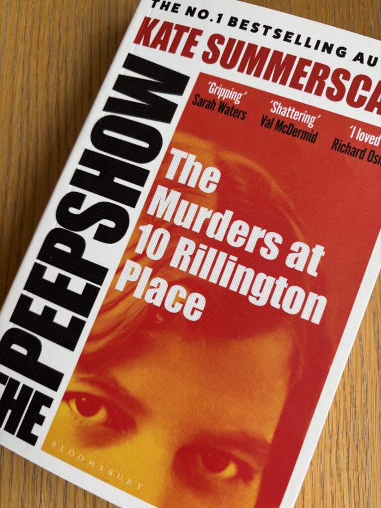 Book review, The Peepshow by Kate Summerscale, 10 Rillington Place, An orange book with a photo of a woman's eyes and forehead called The Peepshow The Murders at 10 Rillington Place by Kate Summerscale sits on a wooden table