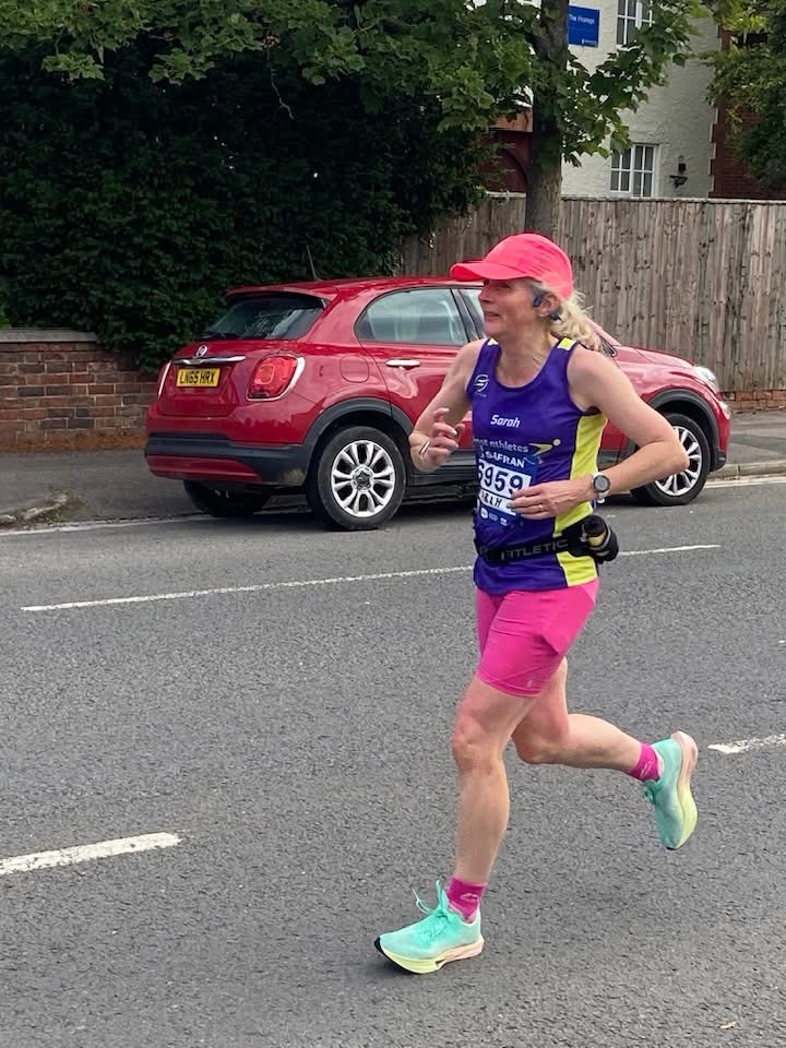 Run Cheltenham, Cheltenham half marathon, Running, Runner, A female runner in a purple vest and pink shorts runs along a road