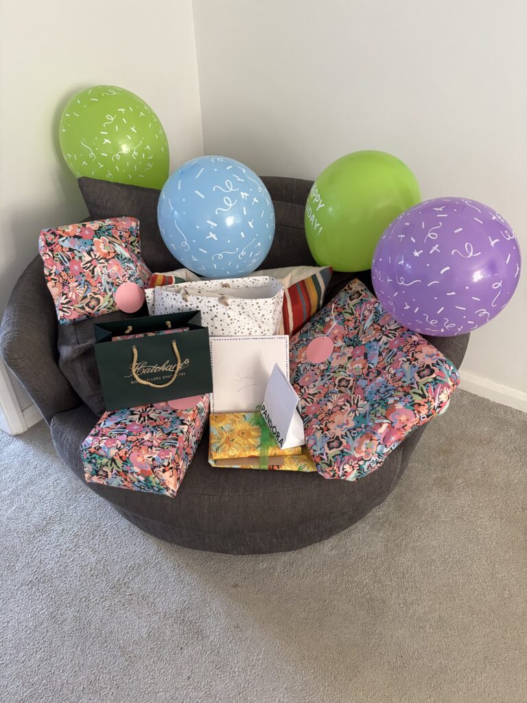 Birthday. Birthday presents, 52nd birthday, Silent Sunday, My Sunday Photo, Birthday presents in a variety of coloured wrappings sit on a round grey chair with four coloured balloons