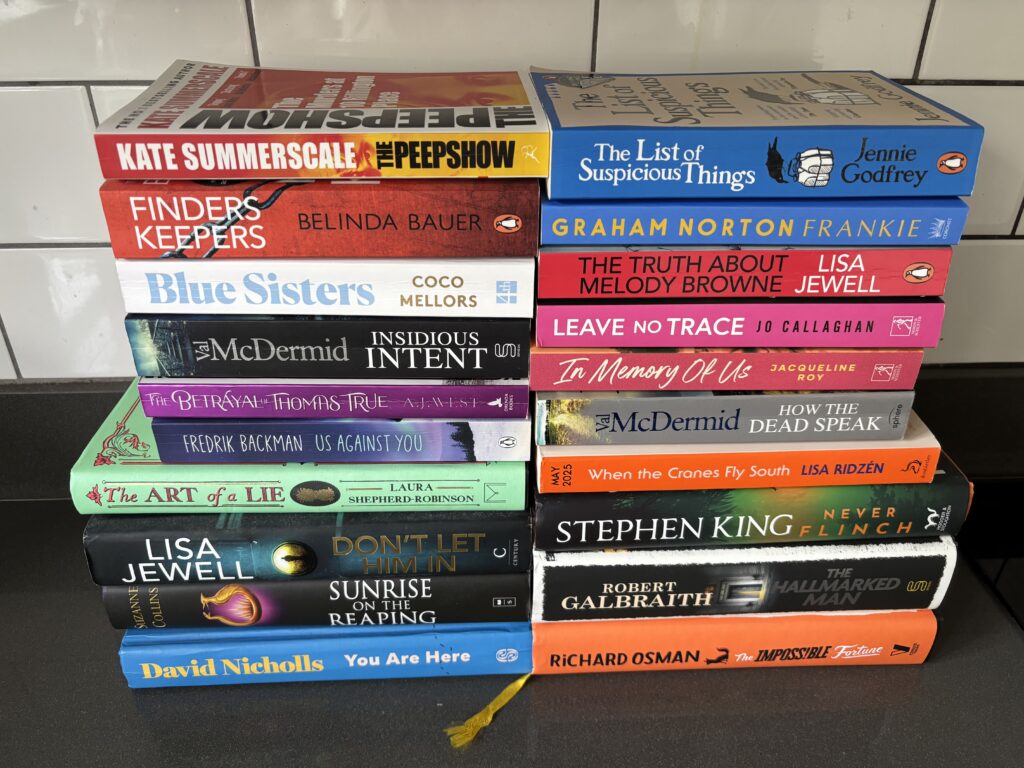 What I read in 2025, Books I read in 2025, Books, Reading, Two piles of around 10 books each sit on a dark surface against a white tiled wall