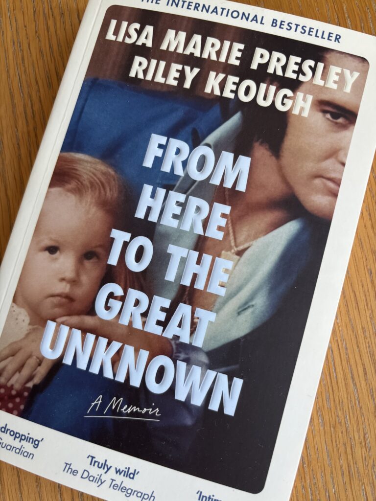 From Here to the Great Unknown by Lisa Marie Presley and Riley Keough, From Here to the Great Unknown, Lisa Marie Presley and Riley Keough, Book review, A book called From Here to the Great Unknown by Lisa Marie Presley and Riley Keough with a dark haired man (Elvis Presley) and a fair haired toddler on the cover sits on a wooden table