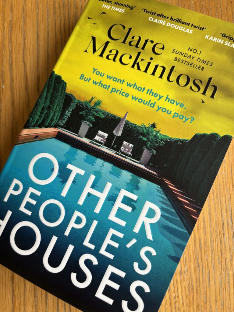 Other People's Houses by Clare Mackintosh, Other People's Houses, Clare Mackintosh, Book review, A book called Other People's Houses by Clare Mackintosh with an outdoor swimming pool and yellow sky on the cover sits on a wooden table