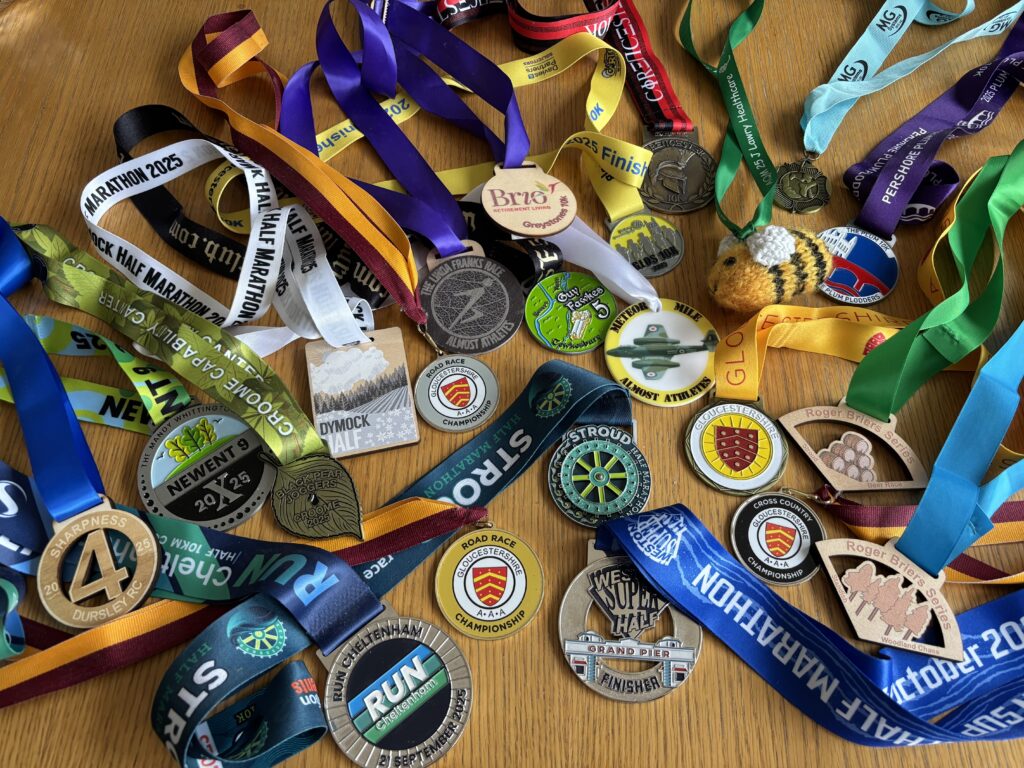 Medals, Running, Runner, A large number of medals of different shapes sizes and colours sits on a wooden table
