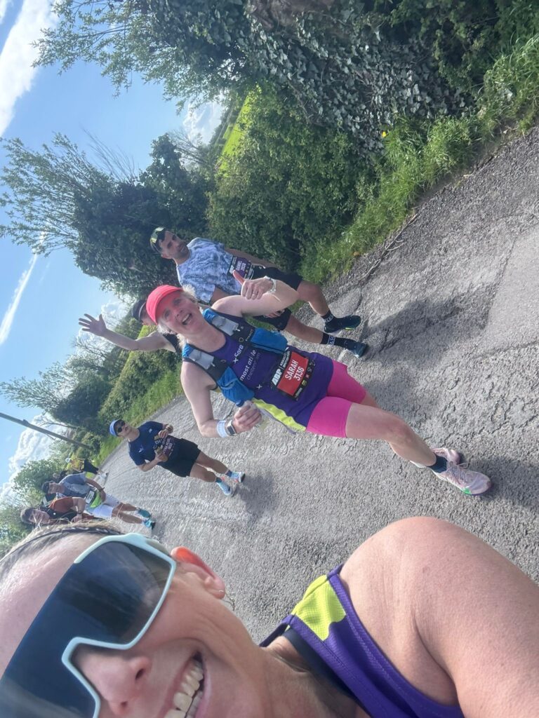 Newport marathon, Running, Runner, A woman takes a selfie showing part of her face in big dark sunglasses with runners on a country lane in the background including a woman in pink shorts and a pink cap