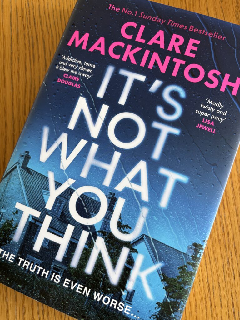 It's Not What You Think by Clare Mackintosh, It's Not What You Think, Clare Mackintosh, Book review, A blue book with houses on the cover and streaked with rain called It's Not What You Think by Clare Mackintosh sits on a wooden table
