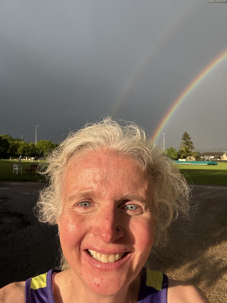 Bourton mile, Rainbow, Head and shoulders of a smiling woman against a black sky with a bright double rainbow