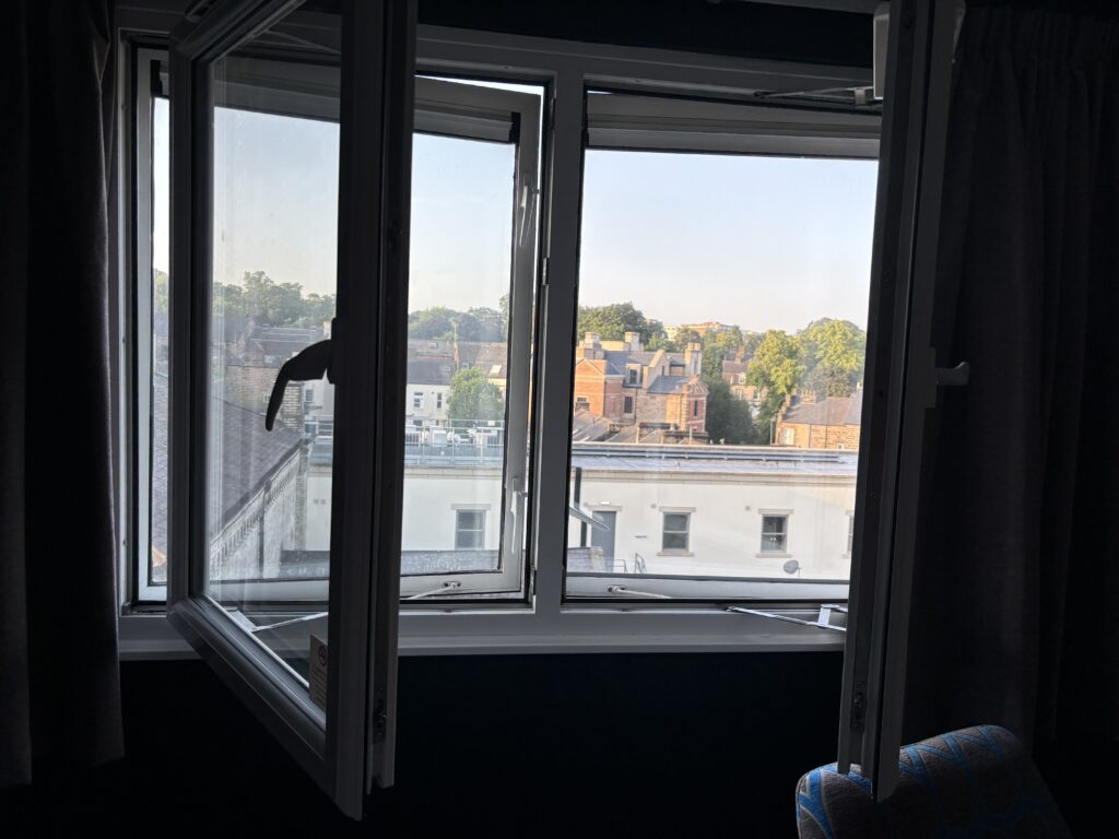 Window, Hotel window, Travelodge window, A window opens into a room with another window behind it open only a crack with buildings visible through it