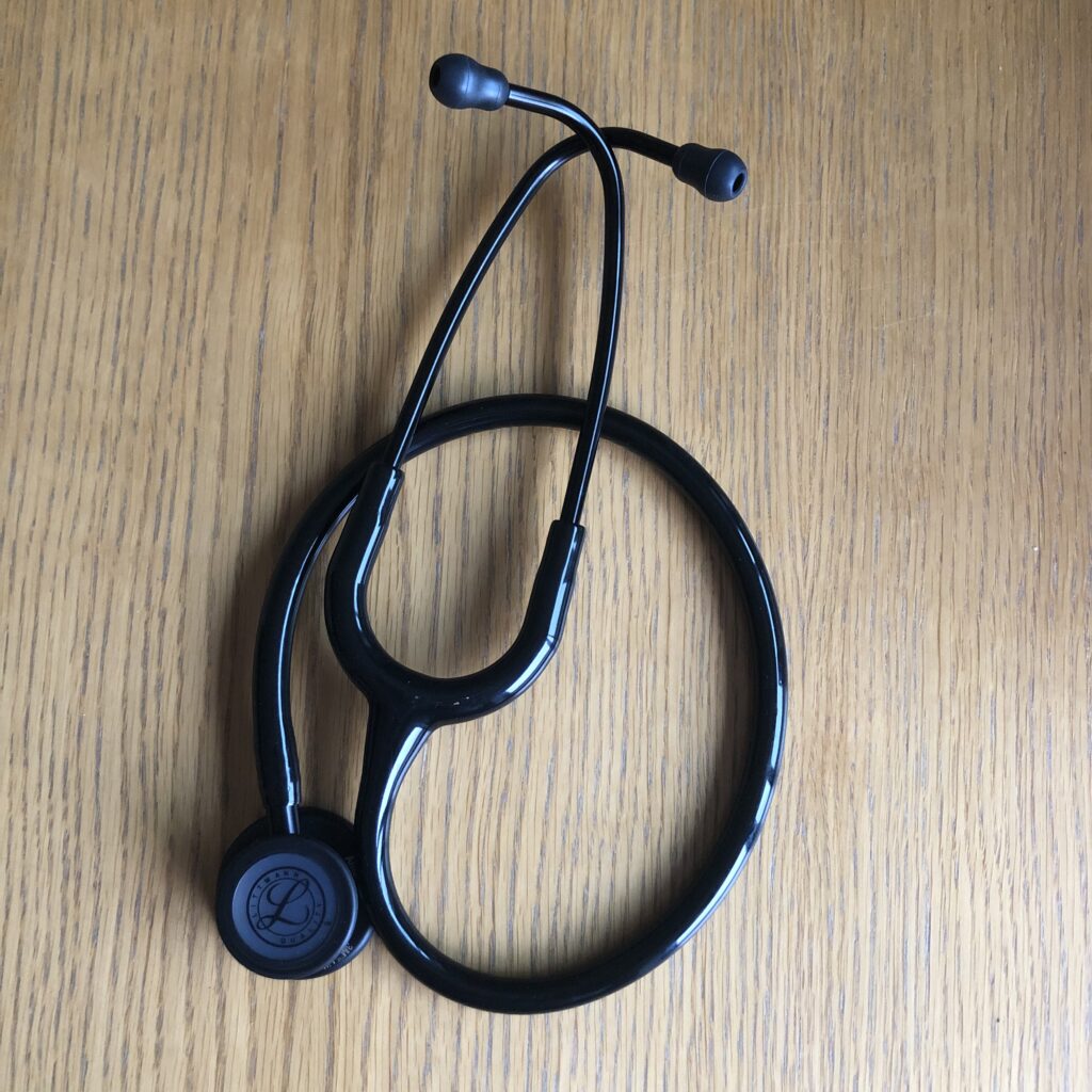 Stethoscope, Studying medicine, A black stethoscope is curled up on a wooden table