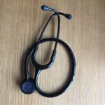 Stethoscope, Studying medicine, A black stethoscope is curled up on a wooden table