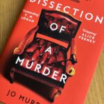 Dissection of a Murder by Jo Murray, Dissection of a Murder, Jo Murray, Book review, A red book with a very formal chair and gavel on the cover called Dissection of a Murder by Jo Murray sits on a wooden table