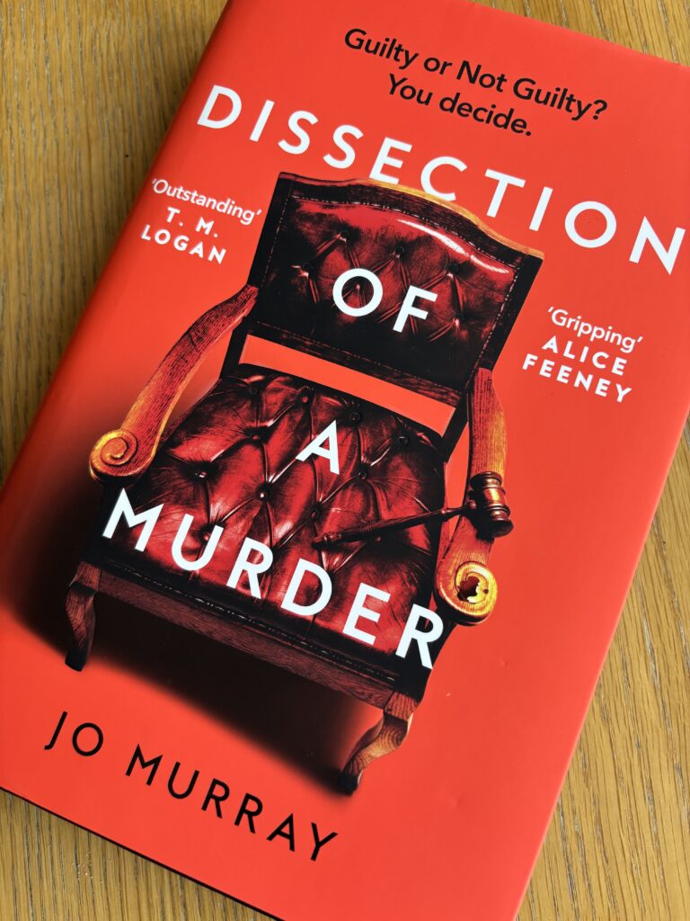 Dissection of a Murder by Jo Murray, Dissection of a Murder, Jo Murray, Book review, A red book with a very formal chair and gavel on the cover called Dissection of a Murder by Jo Murray sits on a wooden table