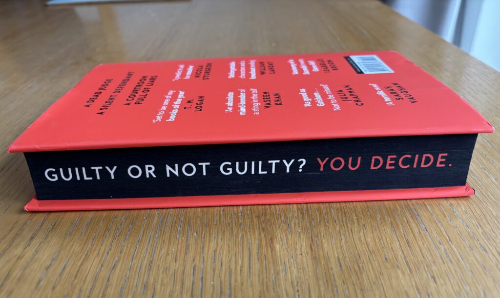 Dissection of Murder by Jo Murray, Dissection of Murder, Jo Murray, Book review, A book with a red cover sits on a wooden table with its pages facing the camera and they are black with the words Guilty or not Guilty? You decide printed on the outside