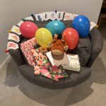 Birthday, Birthday presents, Balloons, 53rd birthday, Silent Sunday, My Sunday Photo, A circular grey chair seen from above is covered in birthday presents and balloons with a Happy Birthday banner draped along the back and a large Pumbaa toy in the centre