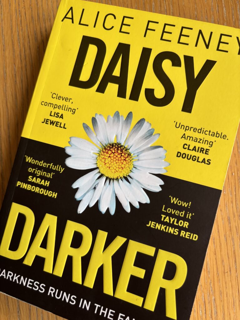 Daisy Darker by Alice Feeney, Daisy Darker, Alice Feeney, Book review, A book called Daisy Darker by Alice Feeney with one half of the cover yellow with black writing and the other half black with yellow writing with a large daisy in the centre sits on a wooden table