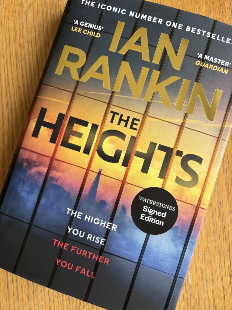 The Heights by Ian Rankin, Book review, The Heights, Ian Rankin, A colourful book called The Heights by Ian Rankin with the silhouette of a landscape including The Shard on the cover sits on a wooden table